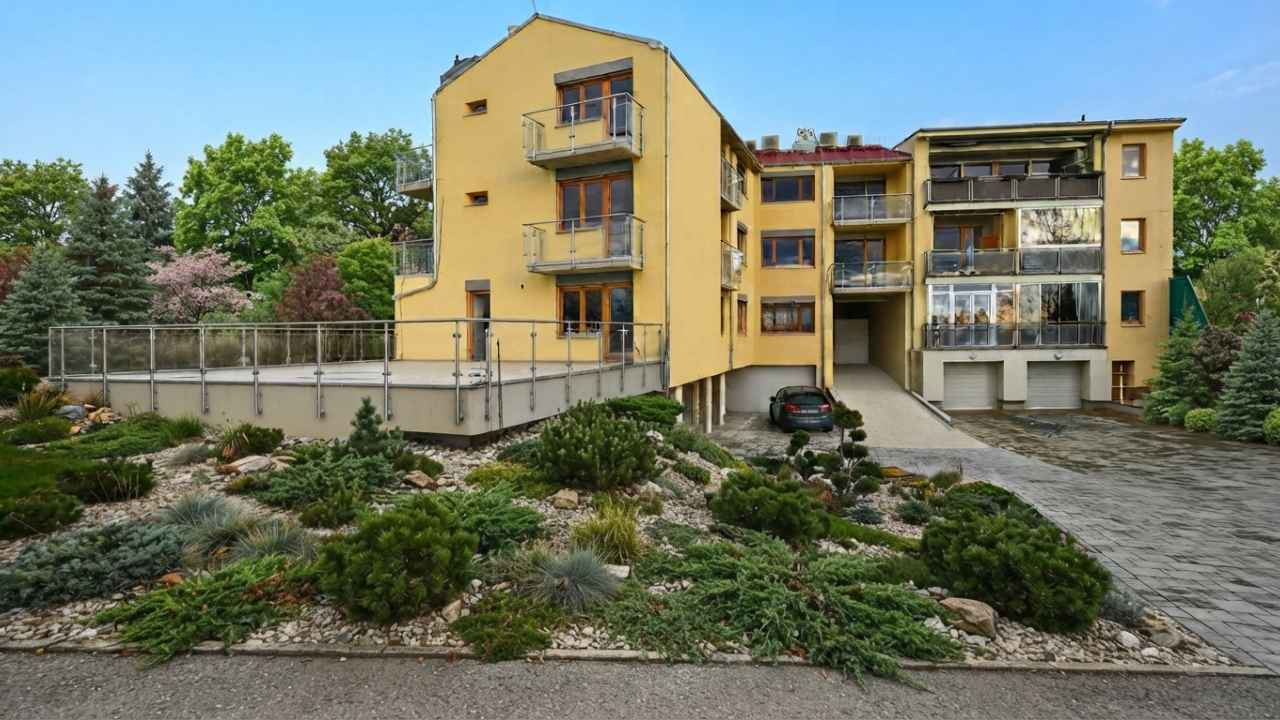 Bytový dům se žlutou fasádou a upravenou zelení v brněnské Líšni, lokalitě pro investiční bydlení.